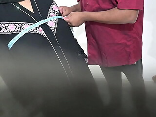 Tailor using hijab lady while taking measurement of blouse