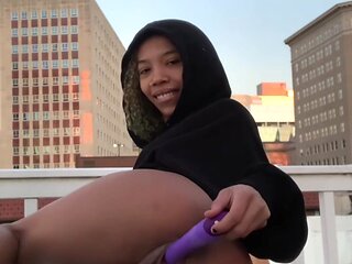 Ebony babe plays with a vibrator on a rooftop showing you her beefy lips