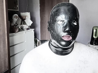 A guy in a latex mask with tubes for his nose jerks off and cums