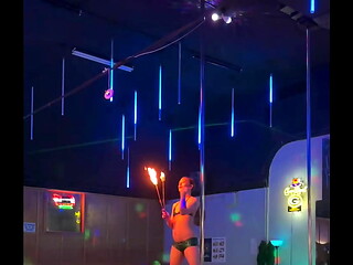 Destiny Mae dancing and playing with fire on stage at the strip club