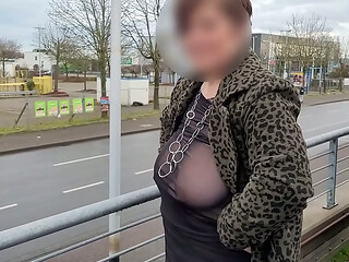 A milf with a sheer top exposed her big tits in the street.