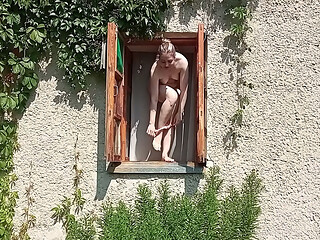 A shameless girl strips and masturbates in an open window