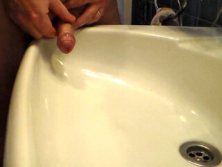 John is peeing into the bathroom sink