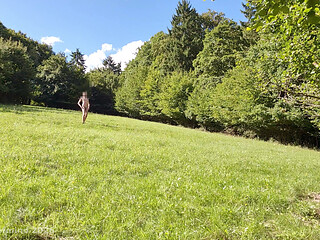 Nude posing in a meadow locked in a steel chastity cage