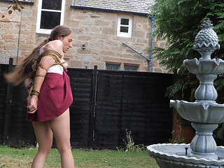 Half-stripped, Bell-jingling Slave Mila Drooling Through Tongue Clamp Is Made to Walk Outdoor Fountain Laps with Crotch Rope Saw