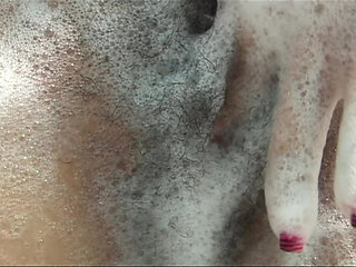 Playful cutie takes a soapy bath and fingers her hairy pussy