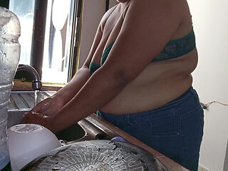 Mother-in-law cleans in the kitchen in bra