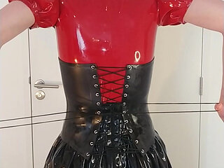Putting on locked rubber corset and long latex skirt over red hooded dress and maid stockings, layers
