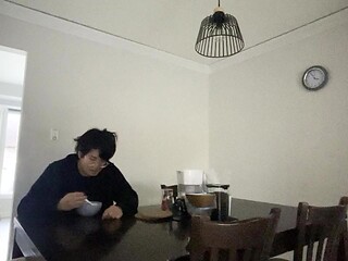 Unhappy Asian teenager cries while eating cereal alone in the dark,