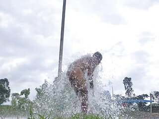 Indian boy stripped naked and bathed in a field