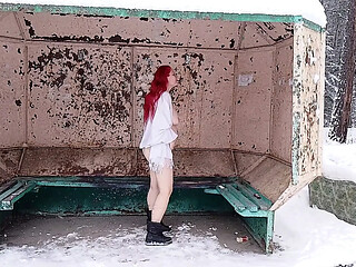 A redheaded girl is playing with her body at a public bus stop in winter!