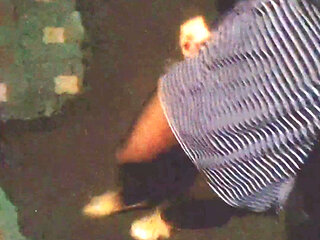 A girl in black stockings with beautiful legs walks down the street at night, showing an anal dildo remote control under skirt