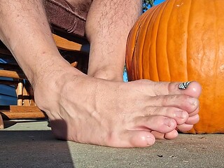 Sexy girl shows off her pedicured feet next to a pumpkin
