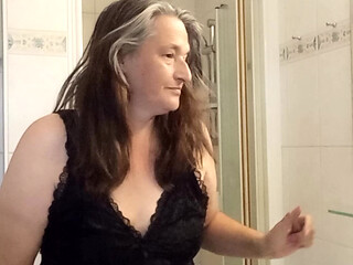 Mature woman with real silver strands slowly combs her long hair