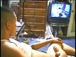 Latino in wifebeater watches TV as he jerks his meat