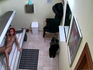 Red MILF rubs her pussy in solarium