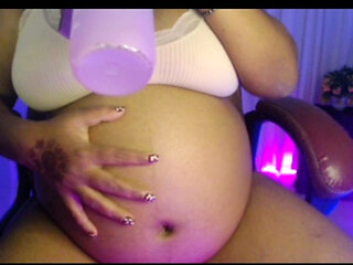 Pregnant lady in penty bra with playing belly and drinking water.