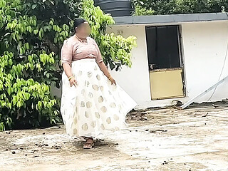 A curvy woman in a white skirt and pink top takes off her clothes,