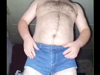 A fat-assed gay man masturbates his cock in ripped denim shorts and black stockings!