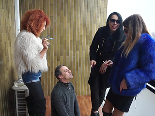 Fur-clad Femdoms Dominate Submissive on Balcony