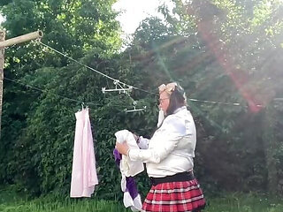 In schoolgirl outfit to hang the laundry