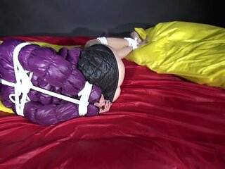 Watching Sexy Sonnja Wearing A Black Shiny Nylon Down Skirt And A Purple Downjacket Being Tied And Gagged With Ropes And A Ballgag On A Bed (Video)