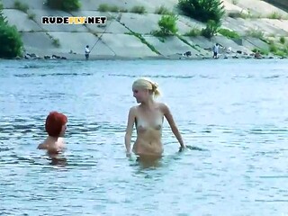 Two young nudist ladies fool around on the beach