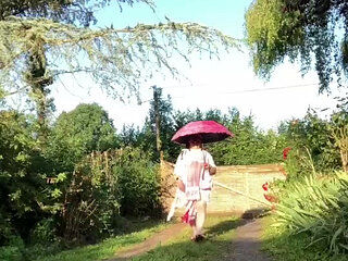 In an outfit with a pink nightgown and a sheer white dressing gown with a parasol